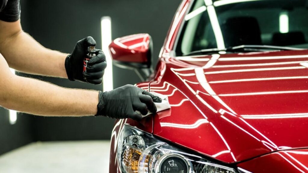 Man applying a ceramic coating to a red vehicle